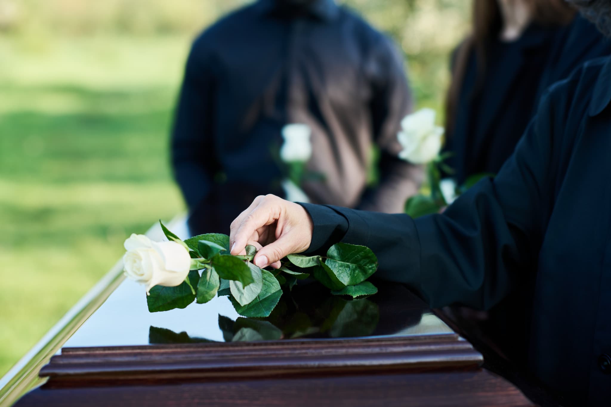 Frau legt Rose auf Sarg