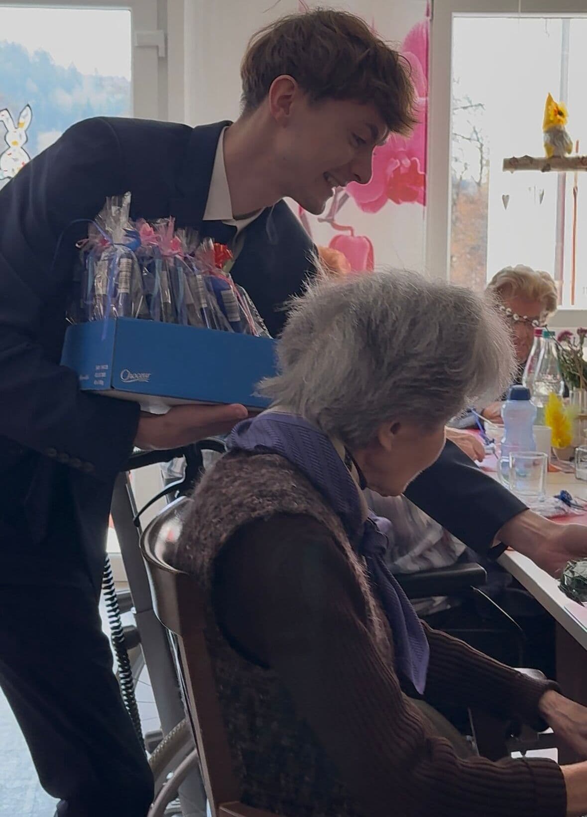 Mitarbeiter überreicht Geschenkbox an Seniorin