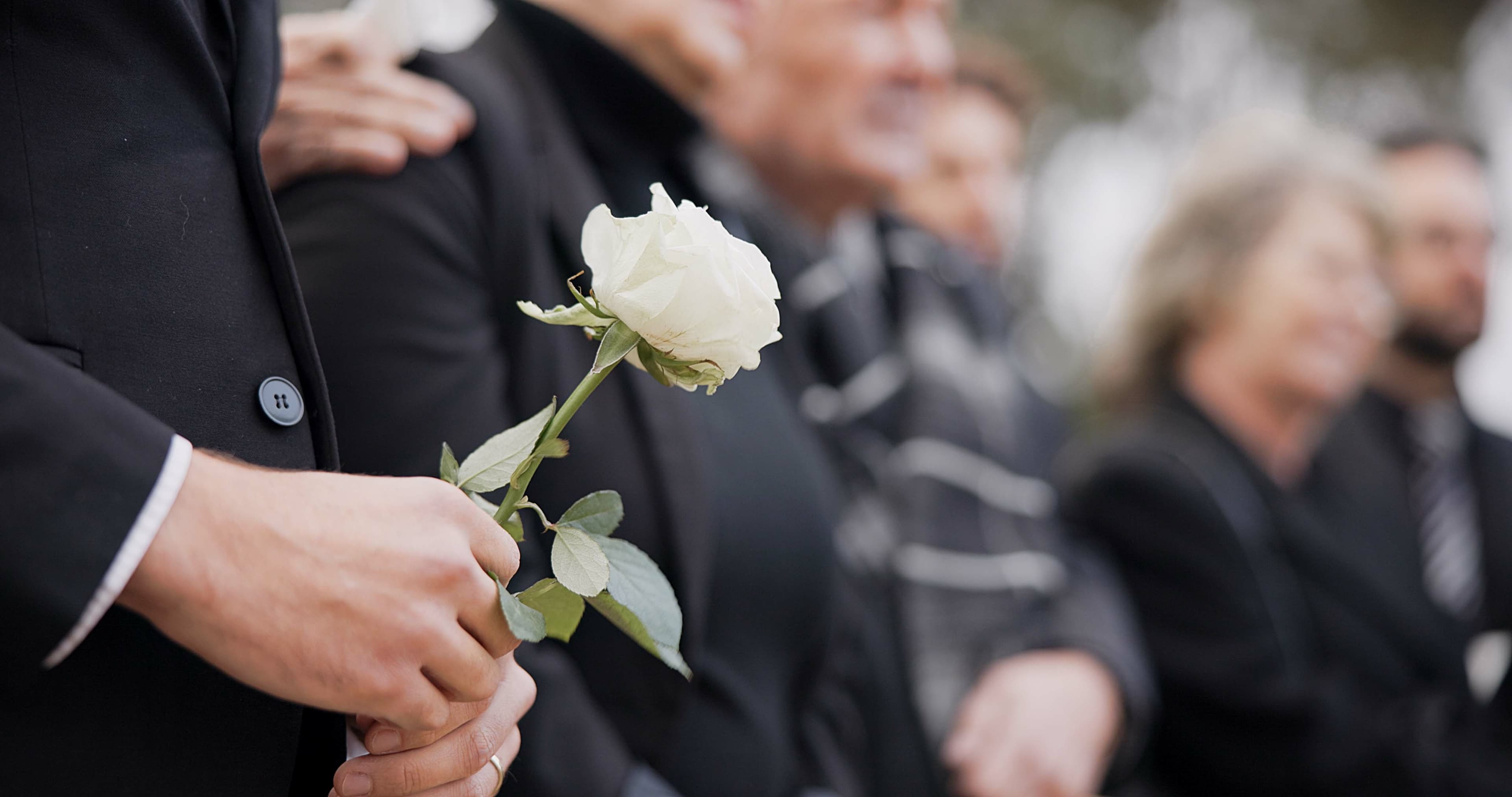 Mann hält Rose auf Trauerfeier