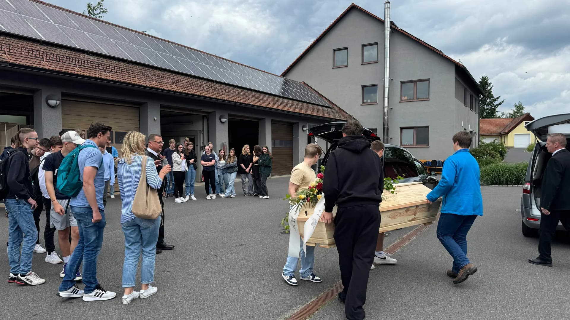 Sargträger überführen Sarg zum Leichenwagen