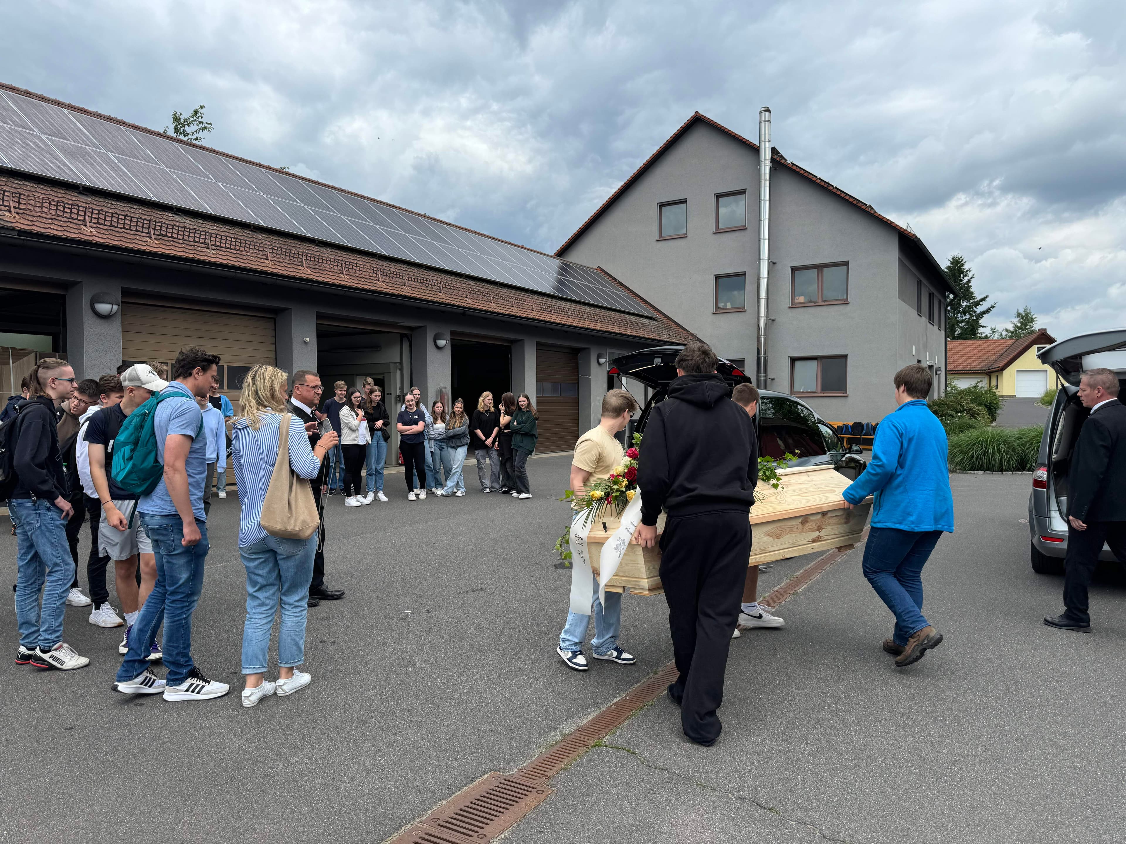 Sargträger überführen Sarg zum Leichenwagen